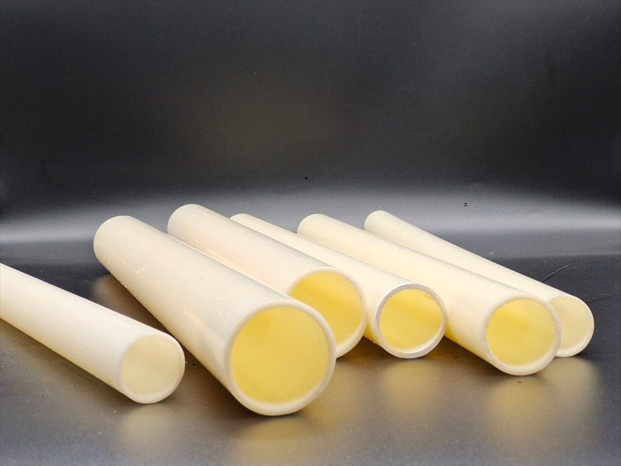 Five ABS pipes laid diagonally on a dark background