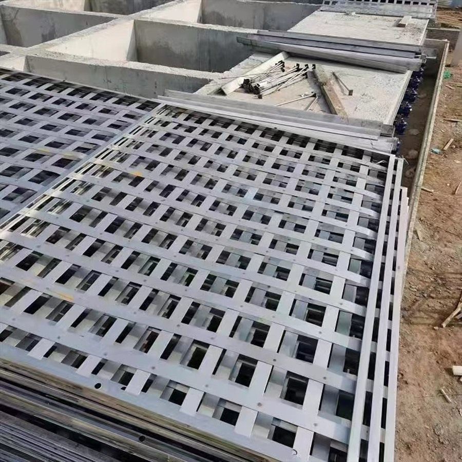 Stainless steel flocculation grid panels stacked beside a concrete basin