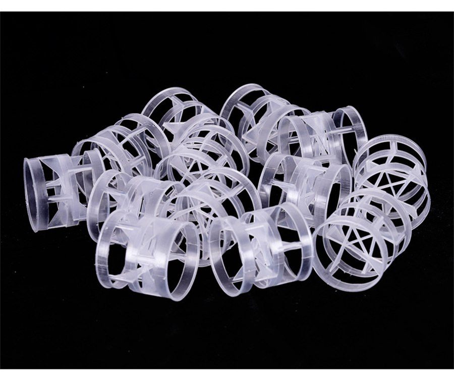 Loose pile of semi-transparent polypropylene Pall rings on a black background