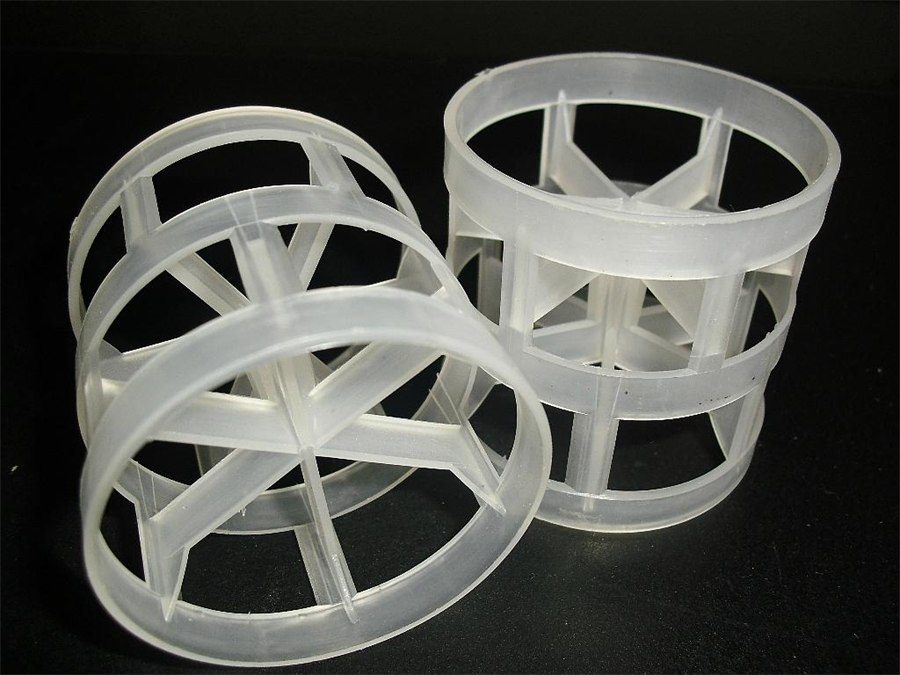 Semi-transparent polypropylene Pall rings with inward conical tongues, two pieces on a black background