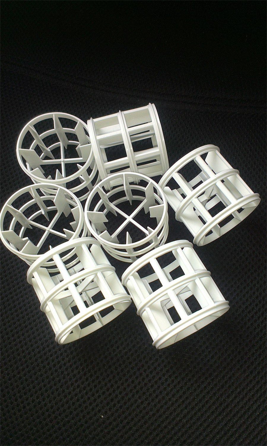 Group of white polypropylene Pall rings on a dark textured background