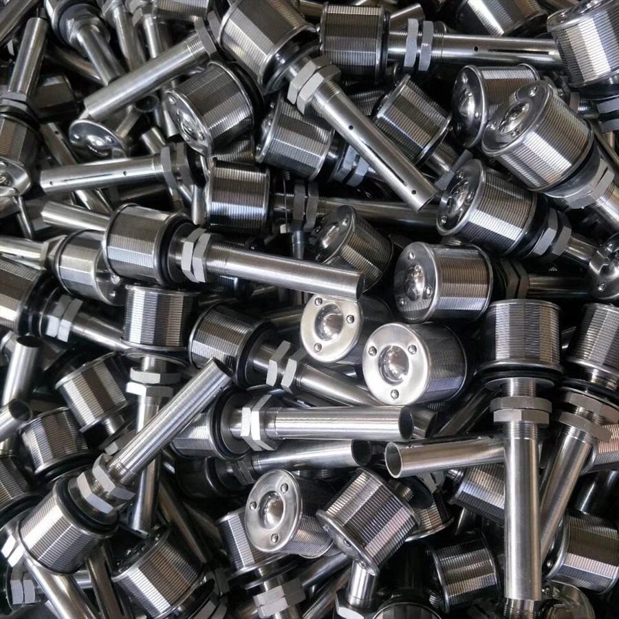 Close-up of stacked drain caps showing wedge-wire cylinders and threaded stems