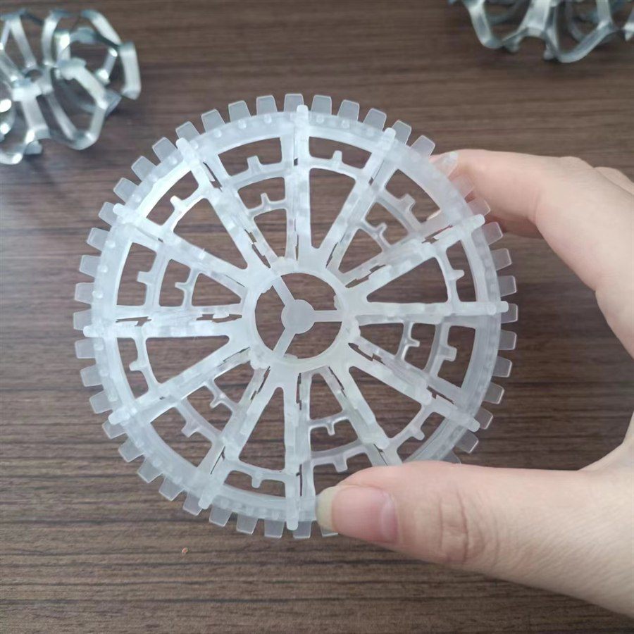 Hand holding a white rosette ring over a wooden table with stainless rings behind